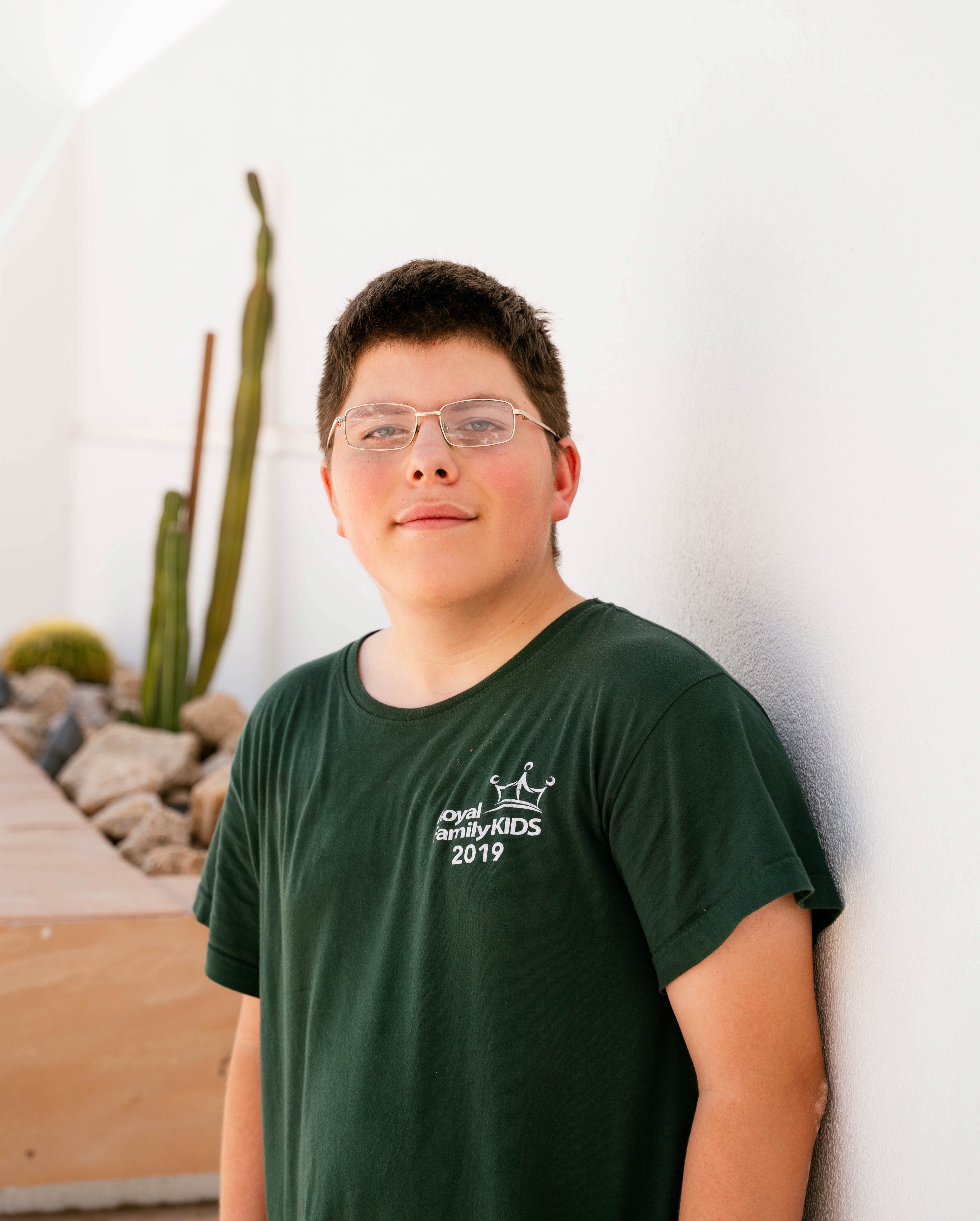 Julyus standing by white wall with cactus in background