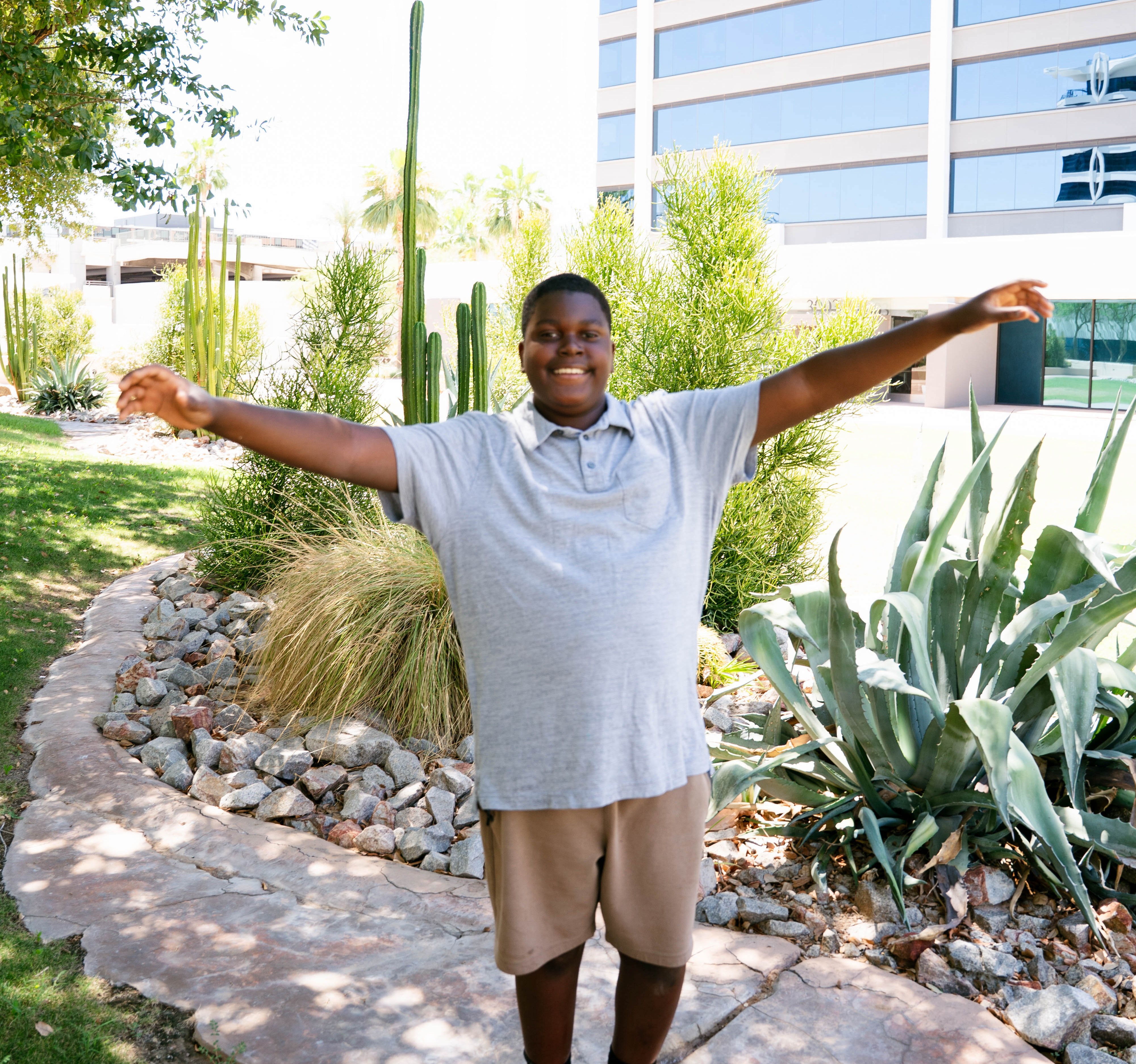 Kevin standing with cactus and arms out.