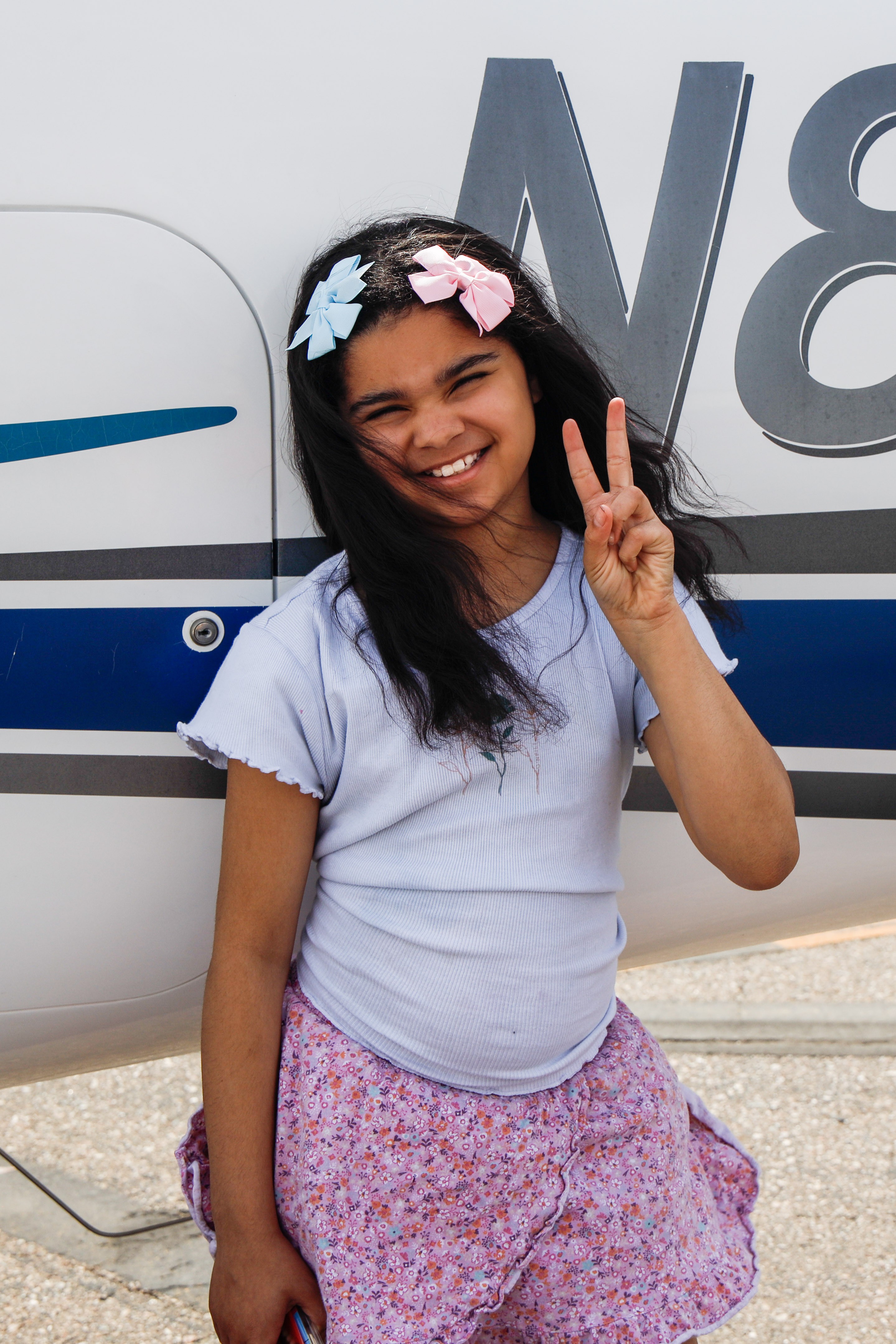 Addy standing by plane with peace sigm