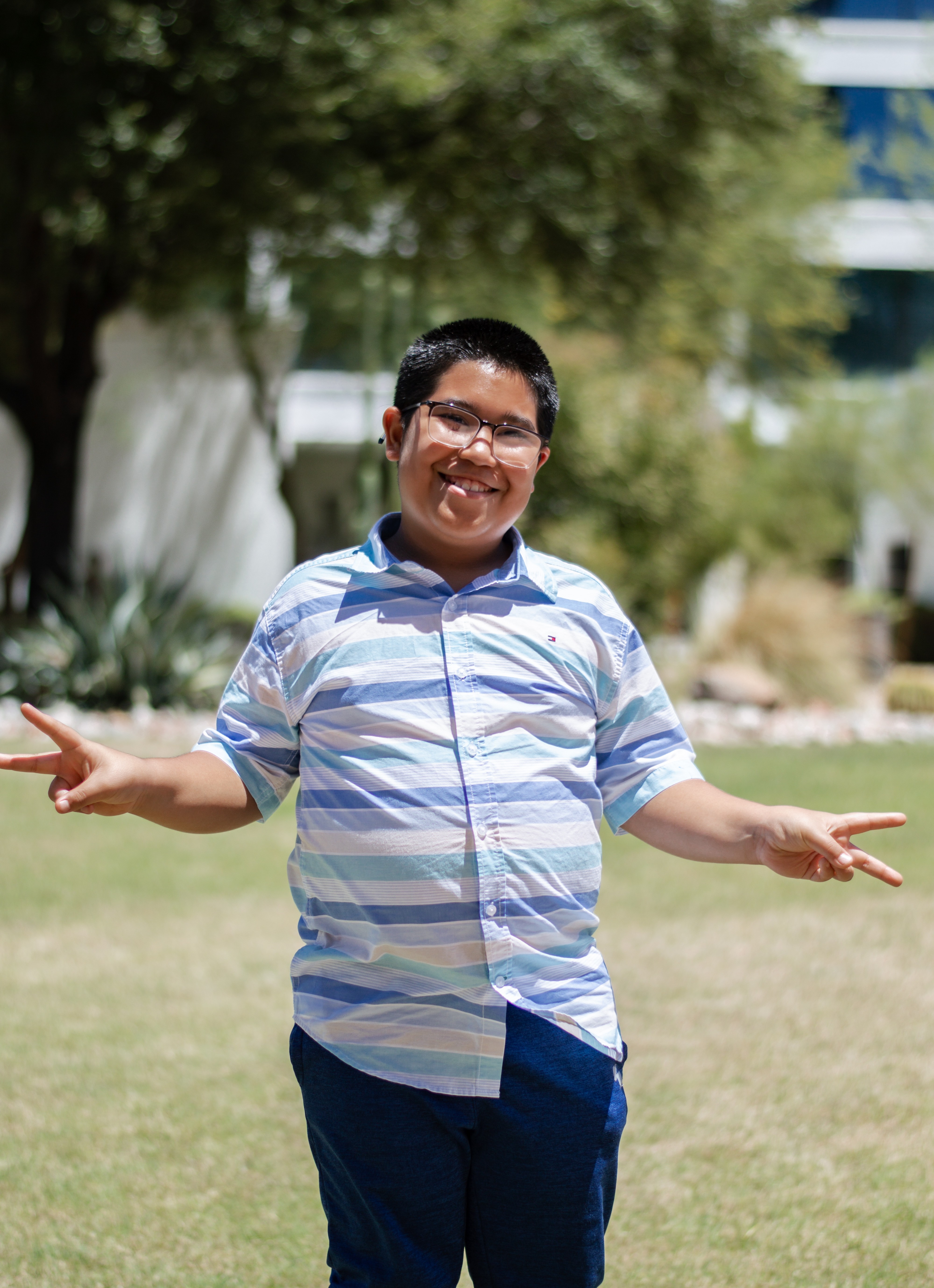 Reyes standing with peace signs in grass with trees in background
