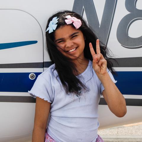 Addy standing by plane with peace sigm