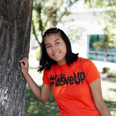 Lizbeth leaning on tree